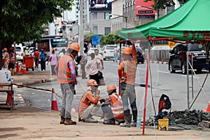 The man are working construction with orange color of safety helmet and safety vest on city background.