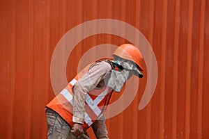 The man are working construction with orange color of safety helmet and safety vest on orange wall background.