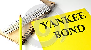 YANKEE BOND text written on a yellow paper with notebook