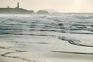 The Yaquina Head Lighthouse in the Mist from the Shore of the Pacific Ocean in Oregon, USA