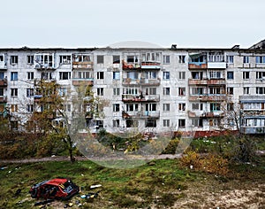 The yard of destroyed apartment buildings in the war zone. Damage to a house as a result of artillery shelling. War in