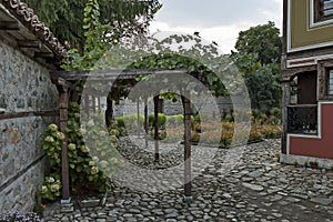 Yard with fragment of old house with interestingly architecture and flower garden in Panagyurishte town