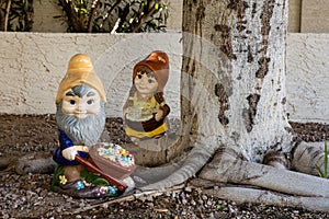 Yard gnomes working in the garden by a tree
