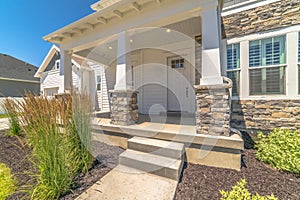 Yard pathway and steps that leads to concrete porch and white front door of home