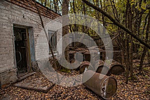 Yard with rusted barrels near abandoned building in Chernobyl ghost town