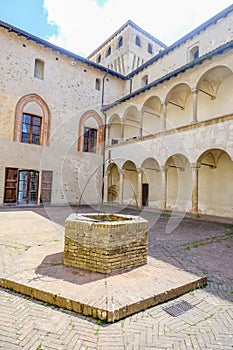 yard with a well of the Castle Torrechiara in Langhirano, Italy across arches and columns inside