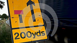 200 yards roadworks warning sign on UK motorway at evening with traffic passing