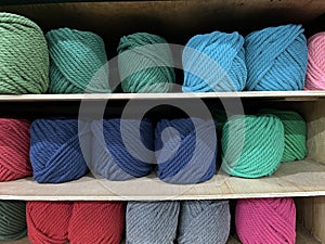 Yarn balls for knitting being arranged on a shelf in a store.