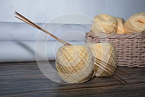 yarn in basket on wooden textured background and crochet needle, stocking needles