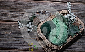yarn in basket on wooden textured background and knitting markers, decorative Christmas branch