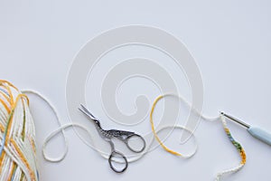 Yarn and crochet hook on white background with vintage scissors