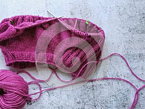 Yarn and knitting needles. Knitting a pink sweater. Rustic grey background.