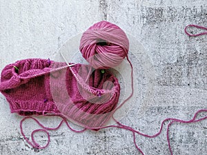 Yarn and knitting needles. Knitting a pink sweater. Rustic grey background.