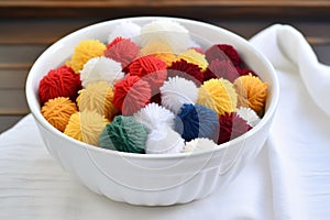 yarn pom poms arranged in a white ceramic bowl