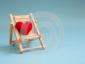 Yarn red heart on the wooden beach chair on blue screen background isolated. copy space for text. Valentines day, love concept a