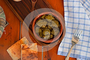 Yarpag dolmasi, yaprak sarmasi, green grape leaves stuffed with rice and meat in pottery bowl.