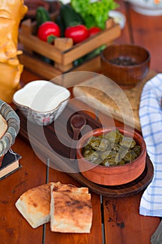 Yarpag dolmasi, yaprak sarmasi, green grape leaves stuffed with rice and meat in pottery bowl with yogurt.