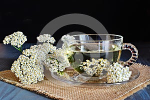 Yarrow medicinal tea in glass cup on dark