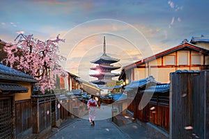 Yasaka pagoda sunset in Kyoto with a young Japanese woman in a traditional Kimono dress during full bloom cherry blossom