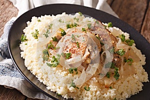 Yassa chicken stewed with marinated onions and couscous close up