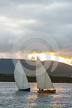 Yawl Racing - traditional sailboat race on Achill Island, Atlantic Ocean on the west coast of Ireland, with a golden sunset in the