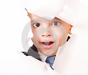 Yawning kid looks through a hole in white paper