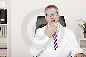 Yawning middle-aged male doctor
