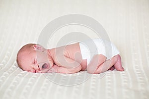 Yawning newborn baby in diaper on knitted blanket