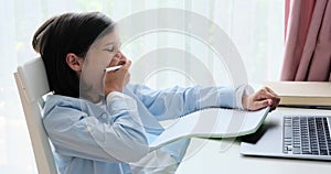 Yawning Schoolboy Working on Homework at the Table