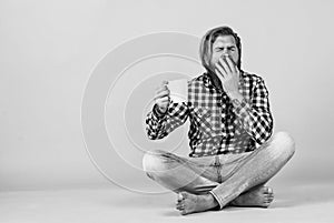 yawning sleepy tired guy. he is taking a coffee break. Handsome mature guy drinking from cup. Hold cup of coffee or tea