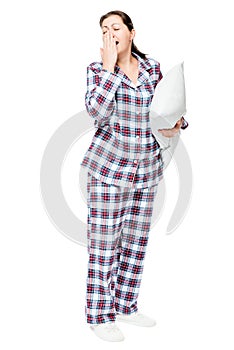 Yawning sleepy woman in warm pajamas holds ready pillow on white