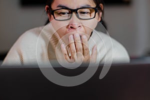 Yawning and sleepy woman working on laptop in office at home. Tired businesswoman wearing eyeglasses using laptop sitting in