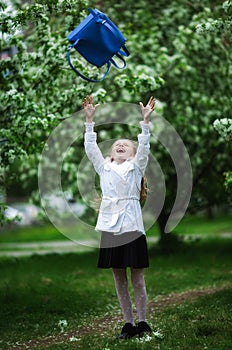 Yay, vacation! Happy girl in school uniform cheerfully throws up school bag. The concept of pre-school education photo