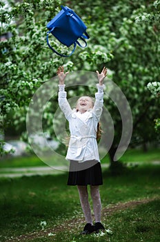 Yay, vacation! Happy girl in school uniform cheerfully throws up school bag. The concept of pre-school education