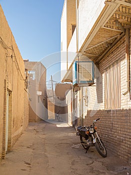 Two motorcycyles standing in a typical street of the old town of Yazd, iran, with its typical clay walls photo