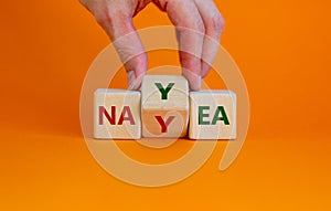 Yea or nay symbol. Businessman turns a cube  changes the word 'nay' to 'yea'. photo
