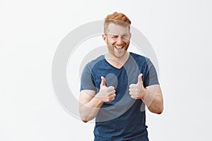 Yeah boy nice choice. Portrait of good-looking male friend with ginger hair showing thumbs up and winking with hint