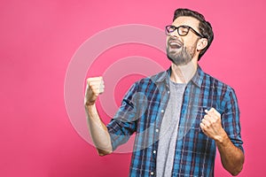 Yeah! Happy winner! Happy young handsome man gesturing and keeping mouth open while standing against pink background