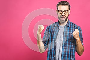 Yeah! Happy winner! Happy young handsome man gesturing and keeping mouth open while standing against pink background