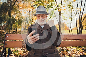 Yeah october sunny weather. White grey hair old man rest relax fall town park sit bench use smartphone check internet