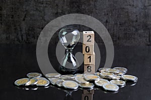 Year 2018 financial or investment time or goals concept with hourglass or sandglass and stack of coins and cube block with number