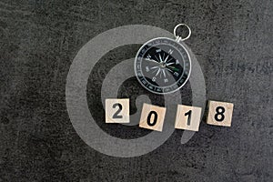 Year 2018 prediction or direction concept with compass and wooden block number 2018 on dark black background