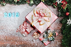 Year 2019 blue color overlay on wood board, red gift boxes at the side have snow all over.