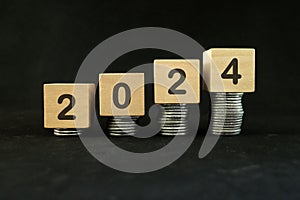 Year 2024 financial success and economic recovery concept. Increasing stack of coins in wooden blocks.