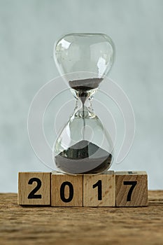 Year end 2017 business time countdown or improvement review concept as hourglass or sandglass with wooden cube block number 2017