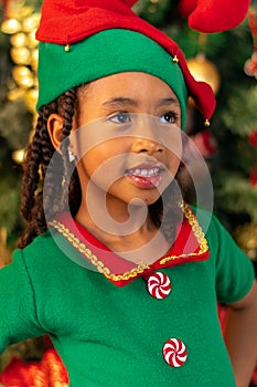 5-year-old Afro-Colombian Colombian Latino girl dressed as an elf next to the Christmas tree photo