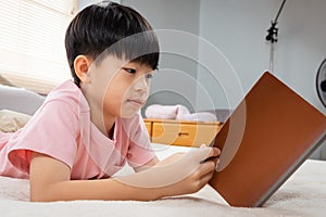 9-year-old Asian boy sitting and reading a book With pleasure, he readily reviewed the things he had learned each day in his bed photo