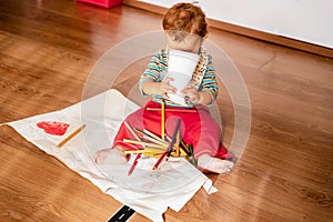 1 year old baby on the floor playing with colored pencils painting