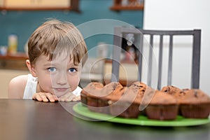 4 year old boy hungrily looking at chocolate cake photo