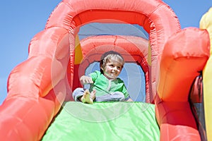 Young boy on inflatable bouncy castle slide at party